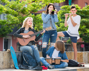 Portrait of four teenagers playing music together outdoors