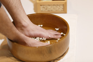 Obraz na płótnie Canvas young man soaking feet in a bowl waiting spa staff to clean.
