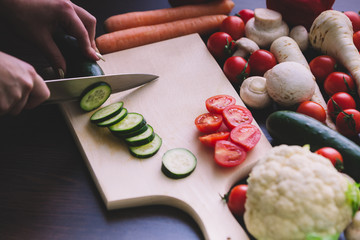 Close up of girl hands while cutting cucumber.