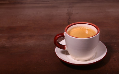 A cup of espresso coffee on a dark wooden background