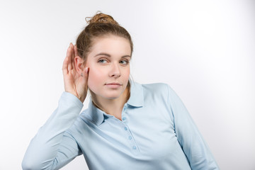 Junge Frau hält sich die Hand ans Ohr und lauscht