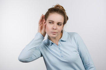 Junge Frau hält sich die Hand ans Ohr und lauscht