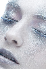 A young girl in the image of a winter beauty. A beautiful model with white skin, sparkles and snowy hair. Shining skin. Winter image. White isolated background. Photo taken in the studio. Close up.