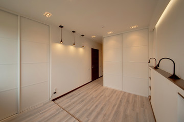  The light white bedroom with the white built-in sliding wardrobes and lamps
