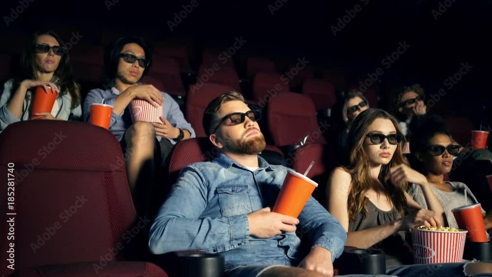 Wall mural Tired bored multiethnic spectators in 3d glasses watching film in cinema