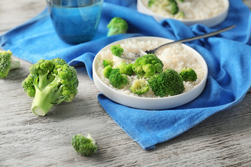 Plate with rice and broccoli on wooden table