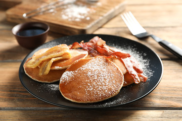 Tasty pancakes with bacon and banana on table