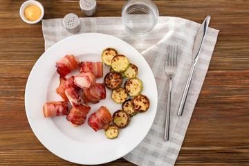 Plate with bacon wrapped chicken nuggets on table