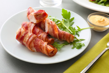 Plate with bacon wrapped chicken nuggets on table