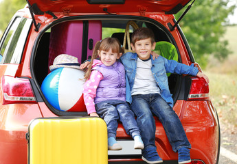 Cute children near modern car prepared for traveling