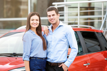 Young couple standing near modern car outdoors