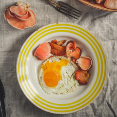 fried eggs with mushrooms (pink oyster mushrooms) serving on a wooden table