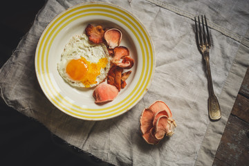 fried eggs with mushrooms (pink oyster mushrooms) serving on a wooden table