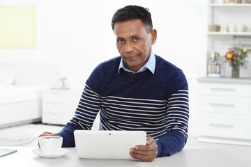 Mature African-American man using tablet computer at home