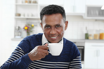 Mature African-American man drinking coffee at home