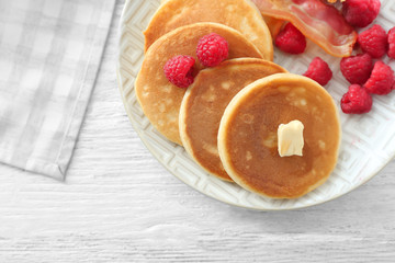 Tasty breakfast with pancakes, bacon and raspberry on plate