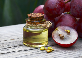Grape seed oil in a glass jar and fresh grapes on old wooden table.Bottle of organic grape seed oil for spa and bodycare and grape  berries.Spa,Bio,Eco products concept.Selective focus. © svf74