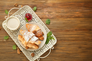 Vintage tray with croissants, jam and cup of coffee on wooden background