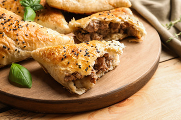Wooden board with delicious meat samosas on table