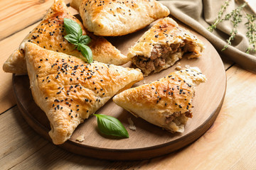 Wooden board with delicious meat samosas on table