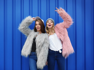 Two happy hipster girls near color wall outdoors