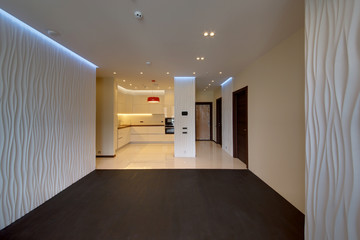 A drawing room with a black wooden floor and with the built-in kitchen