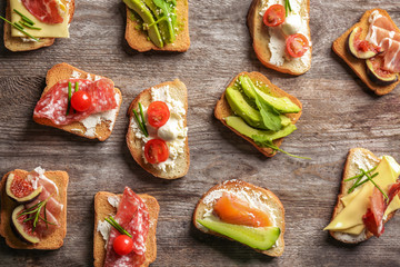 Delicious sandwiches on wooden background, top view