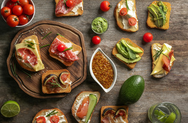 Delicious sandwiches on wooden background, top view