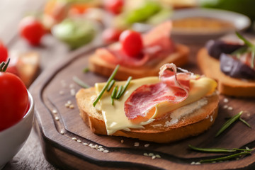 Wooden board with delicious sandwich on table, closeup