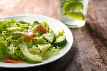 Plate with delicious vegetable salad on wooden background, closeup