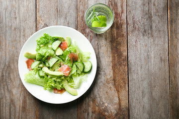Plate with delicious vegetable salad on wooden background, top view