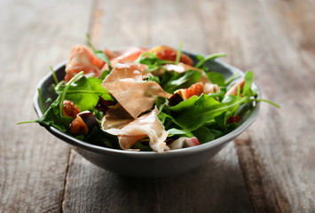 Bowl with delicious salad on wooden background