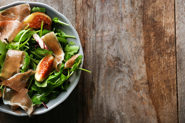 Bowl with delicious salad on wooden background, top view
