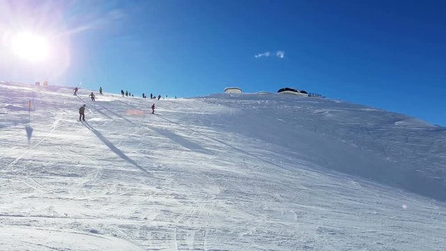 Skiers on the mountain track with the sun behind