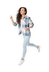 Young woman in casual clothes running against white background