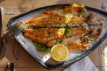 Grilled fish with lemon on a plate.