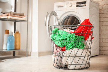 Basket with laundry and washing machine in bathroom