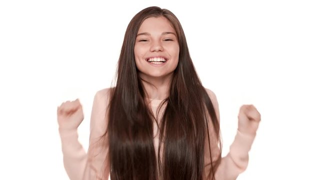 Portrait of young woman 20s expressing surprise and excitement covering open mouth with hands can't believe what happened clenching fists over white background. Concept of emotions