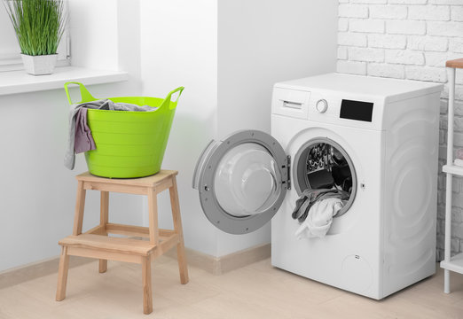 Basket with laundry on stool and washing machine in bathroom