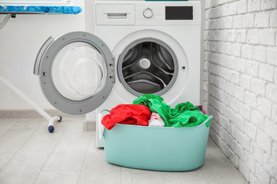 Basket with laundry and washing machine in bathroom