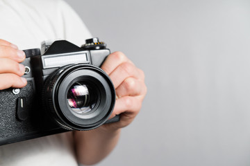 old SLR film camera in the hands of a child in a white t-shirt