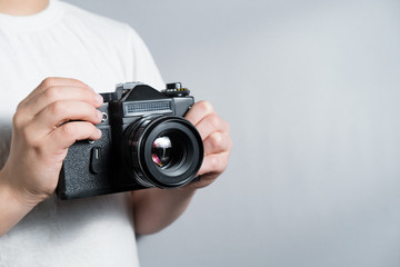old SLR film camera in the hands of a child in a white t-shirt