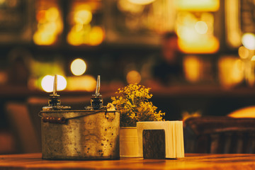 Beautiful restaurant design. Bright interior and lighting. Table in an institution with spices, vinegar and olive olive, paper napkins and flowers in a vase