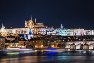 Fototapeta na wymiar Riverbank view of Prague Castle and Charles Bridge and moving boat light trails