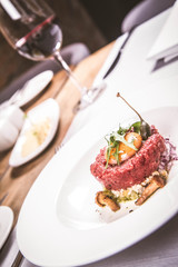 Steak tartare served in a restaurant with egg yolk,  onions, caper, mushroom and rocket salad