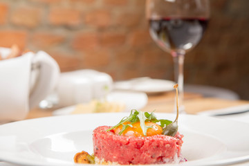 Steak tartare served in a restaurant with egg yolk,  onion, pickles, caper, mushroom and rocket salad