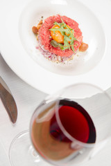 Steak tartare served in a restaurant with egg yolk,  onions, caper, mushroom and rocket salad