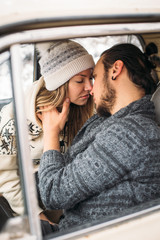 Handsome hipster Man and beauty woman kiss each other sitting in the retro car . Valintine's Day concept. Vertical picture