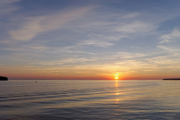 Fototapeta premium A view of the calm golden sunset on the river with the sun reflected in it, Volga, Russia