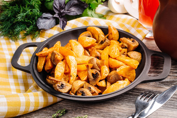 potatoes in a pan with mushrooms  on a wooden table. vegetarian food concept